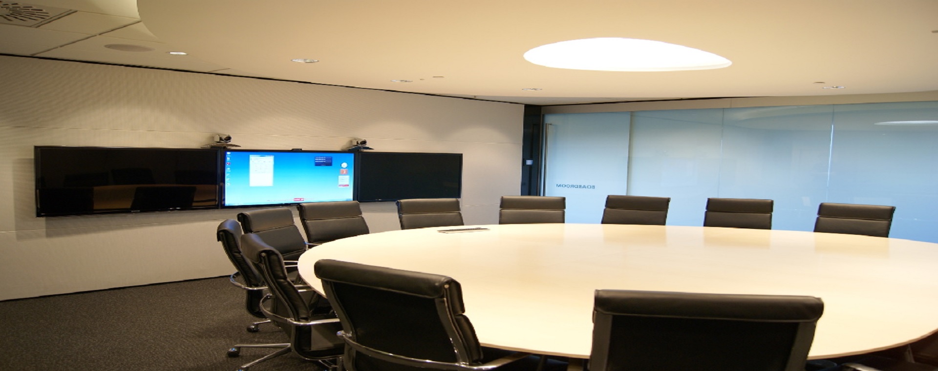 BECA board room with 3 55" commercial display panels for presentations and video conferencing, and a large round table with chairs
