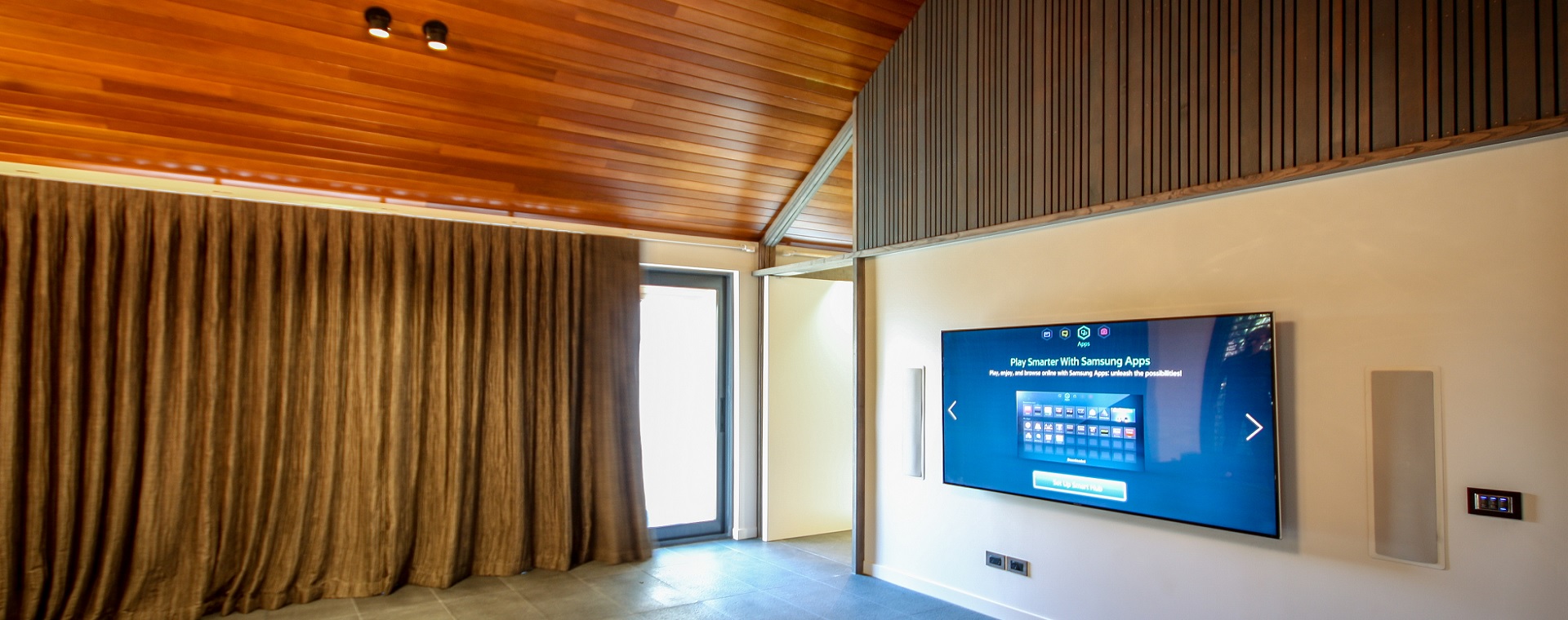 Entertainment room with large TV screen and in-wall speakers for a home theatre experience