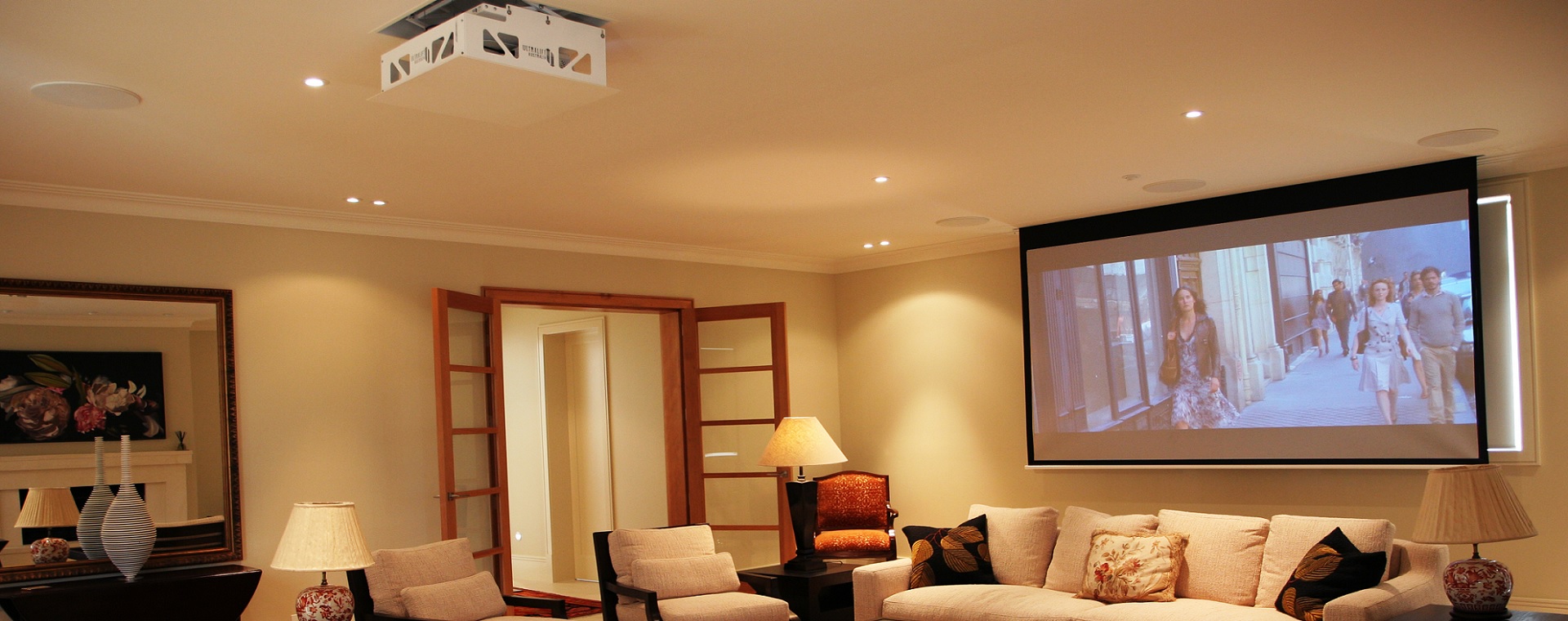 Home theatre with lighting control, drop down projector screen, in-ceiling speakers, controlled via home automation.