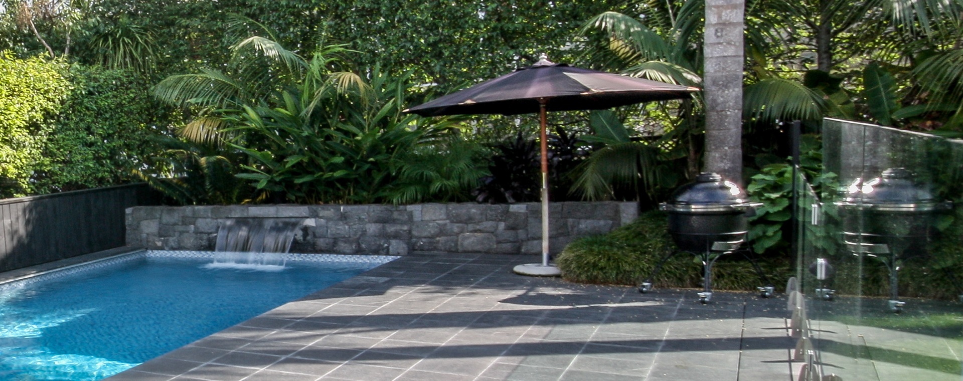 Pool area with umbrella, BBQ and hidden outdoor rock speakers in the garden