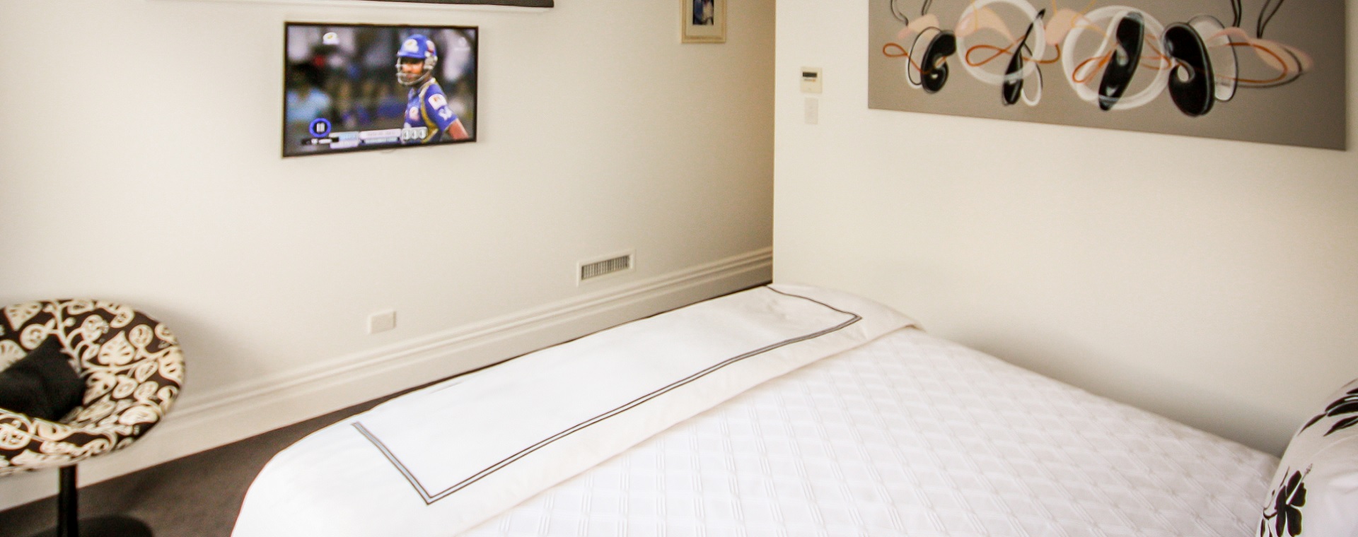 Bedroom with thin bezel TV screen playing an american football game