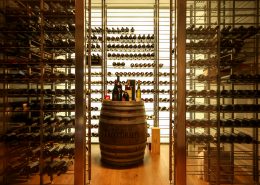 Wine bottles on barrel in a custom wine cellar featuring lighting, refrigeration and humidity control