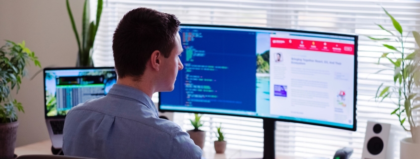 Man working at a wrap around monitor at a desk