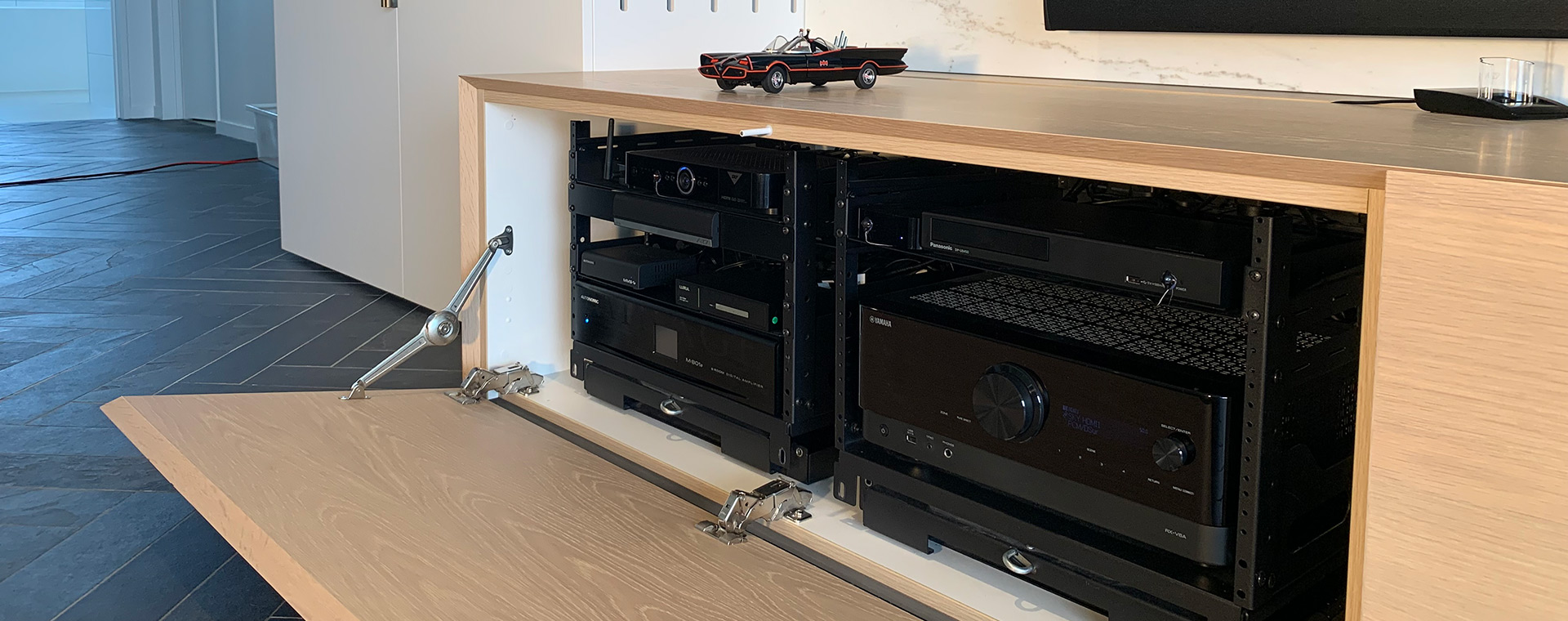 Custom built cabinetry housing entertainment source equipment in AV racks