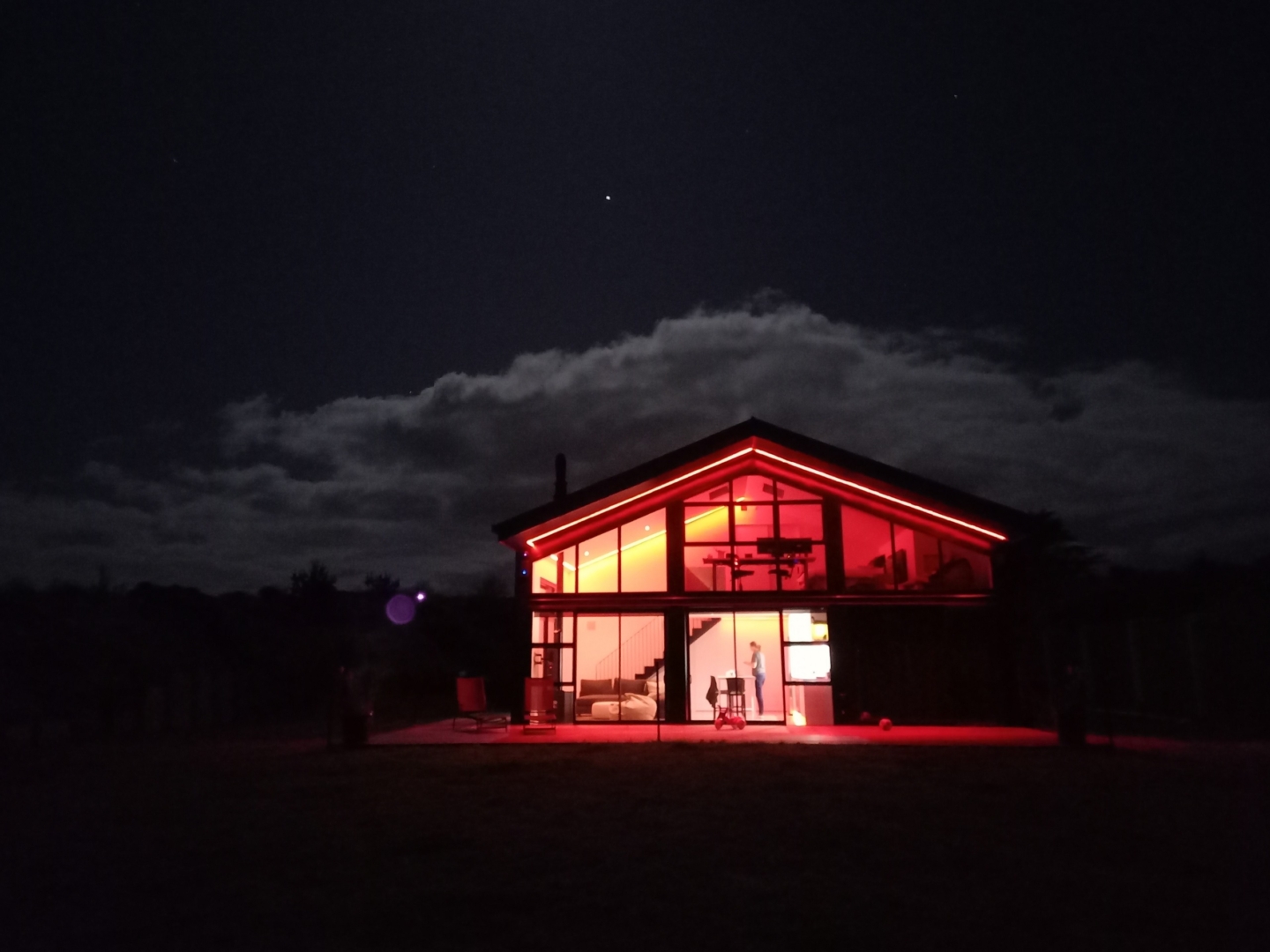 Off-grid home at night, with changeable colour LED details light strips showing red lighting scene.